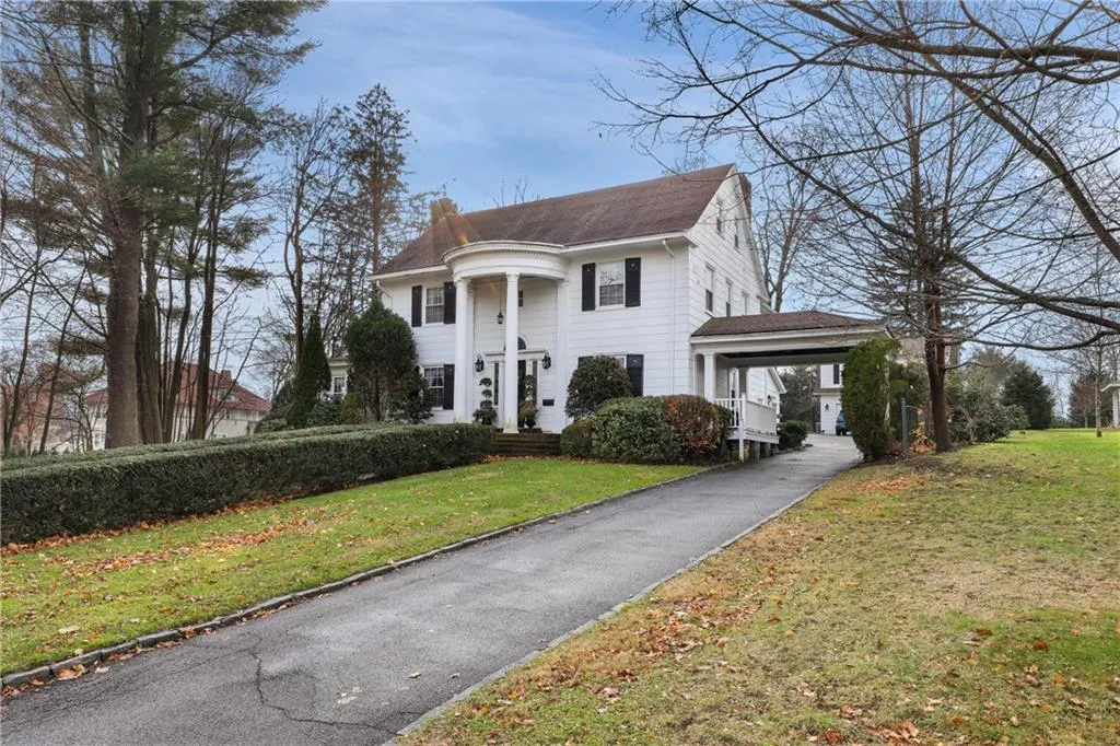 White colonial house at 22 Clark Street in Pleasantville with a columned front portico and a covered driveway entrance