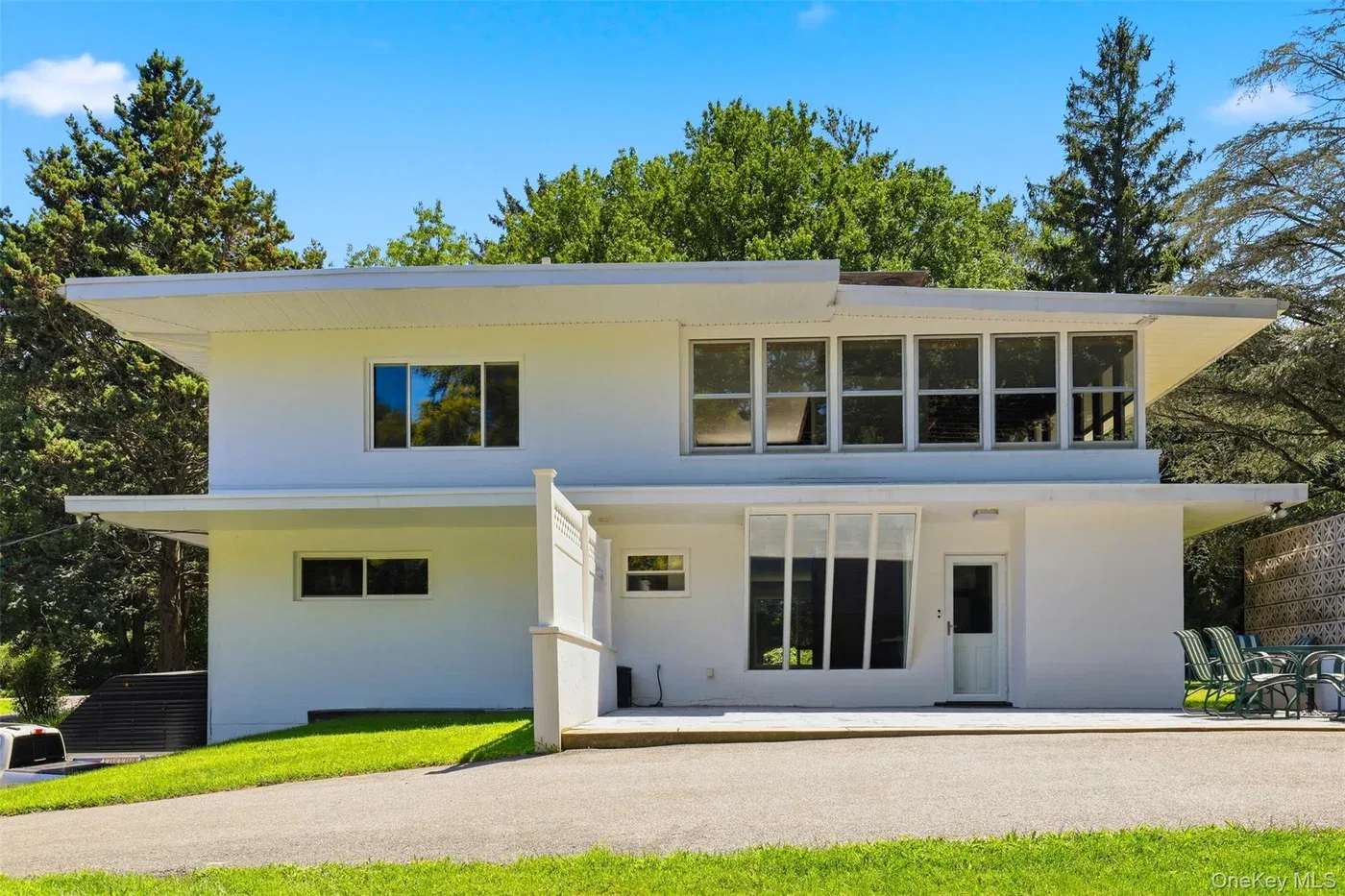 White two-story house at 58 Carolyn Road E in Carmel with deep roof overhangs, a lawn, and tall trees