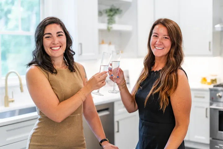 Kayleigh and Catia of The CK Team raising a toast in a bright kitchen
