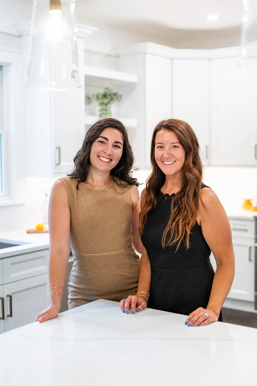 Catia and Kayleigh of The CK Team standing at a white marble kitchen island
