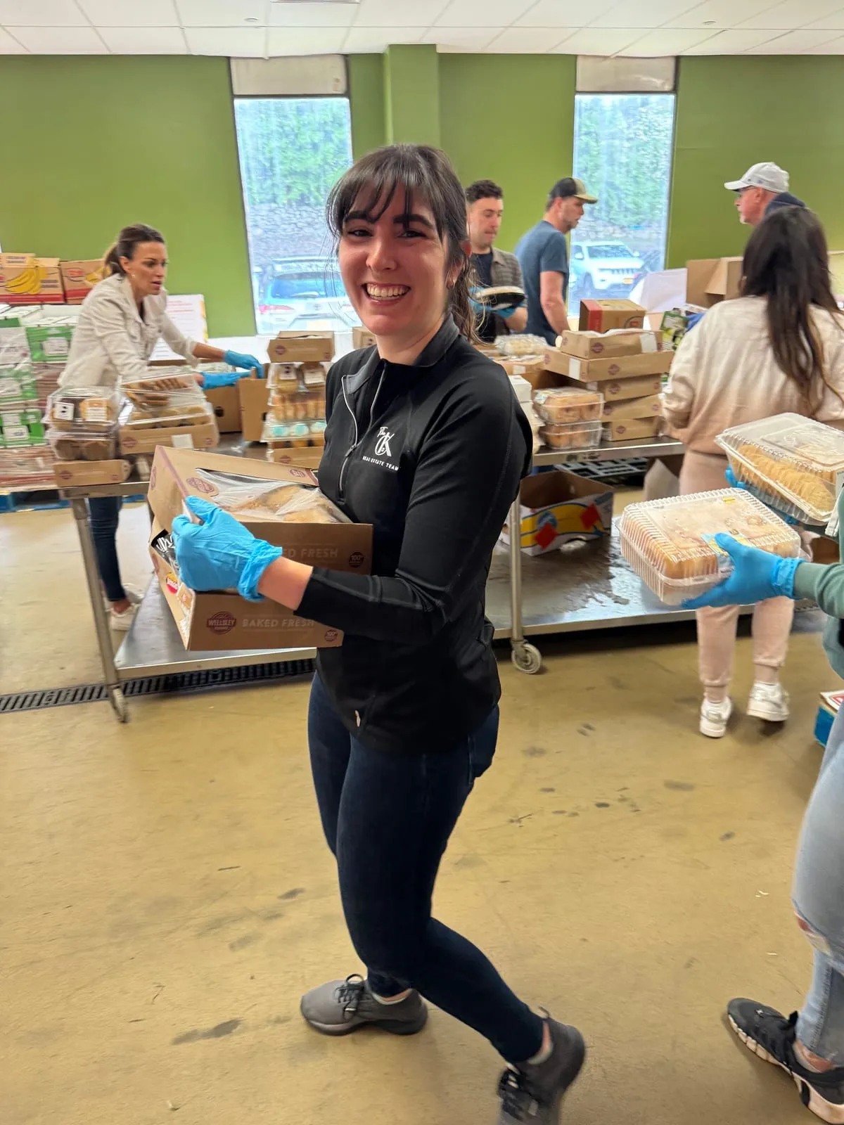 Team member in gloves carrying a box of donated food at a food pantry