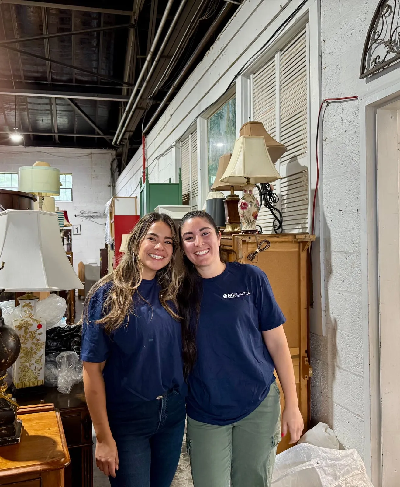 Two team members in HGAR Realtor shirts volunteering at a furniture warehouse
