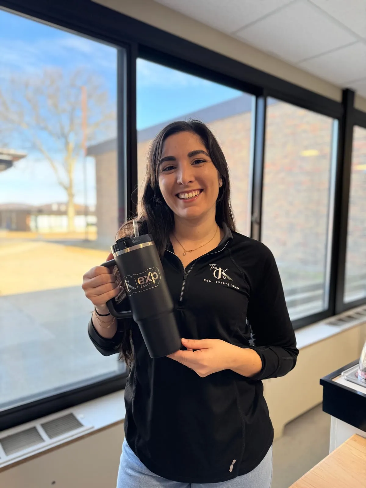 Smiling woman holding a CK Team and eXp Realty tumbler from the giveaway