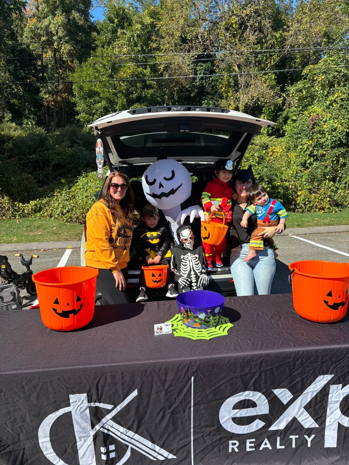 Kids in Halloween costumes with team members beside a decorated SUV trunk