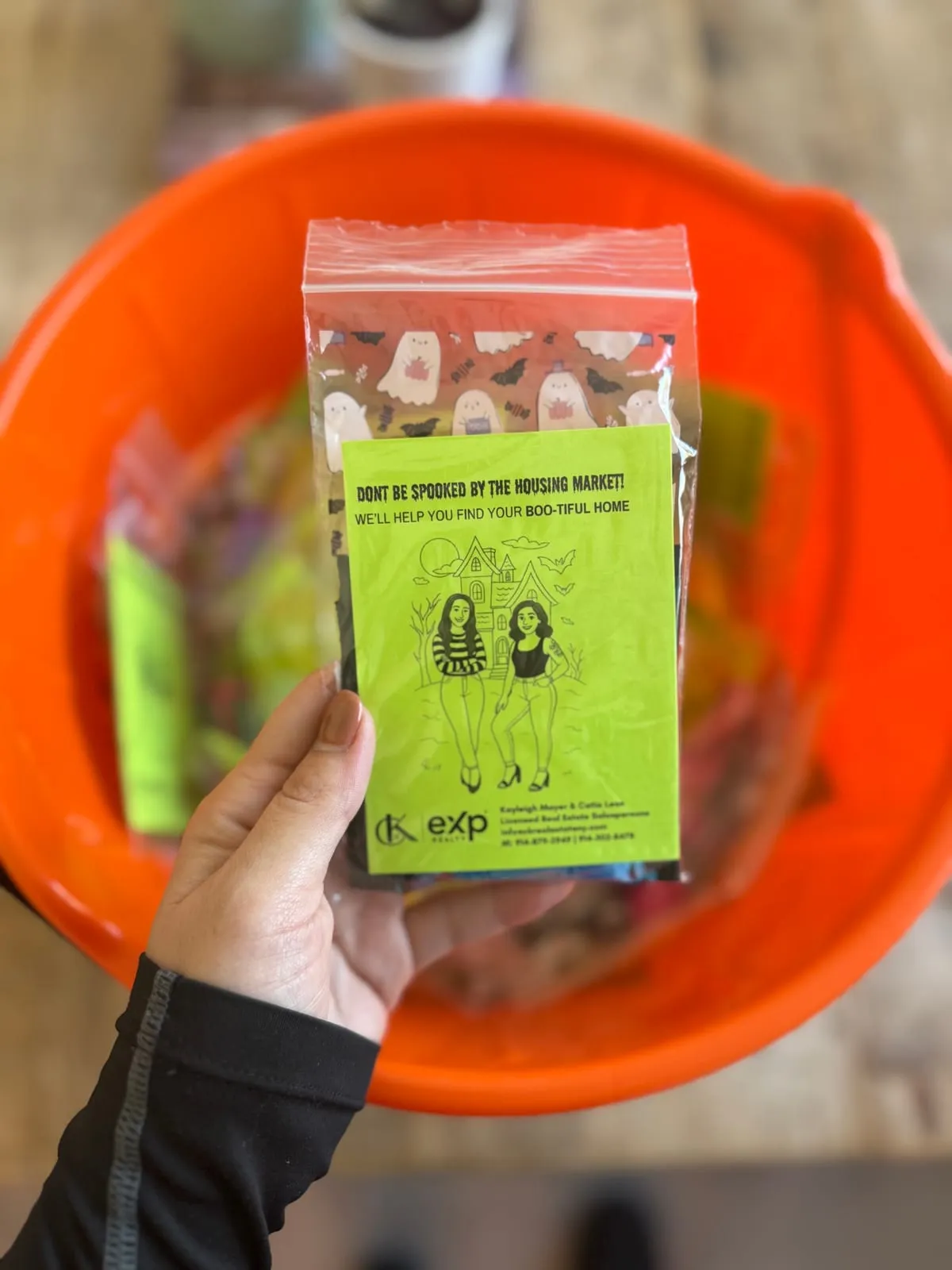 Hand holding a Halloween treat bag with a CK Team card over an orange candy bucket