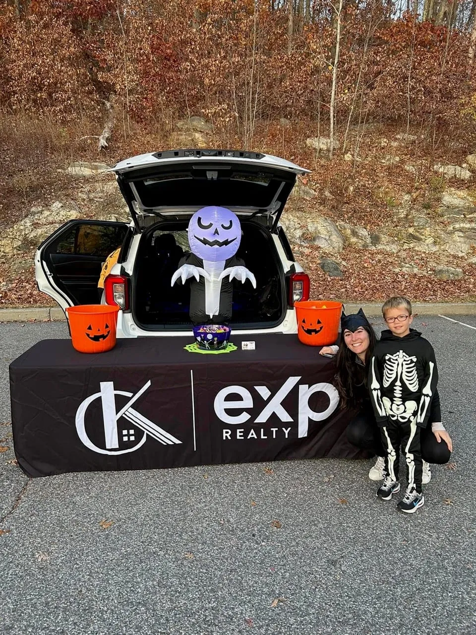 Team member and a child in a skeleton costume beside the CK Team treat table